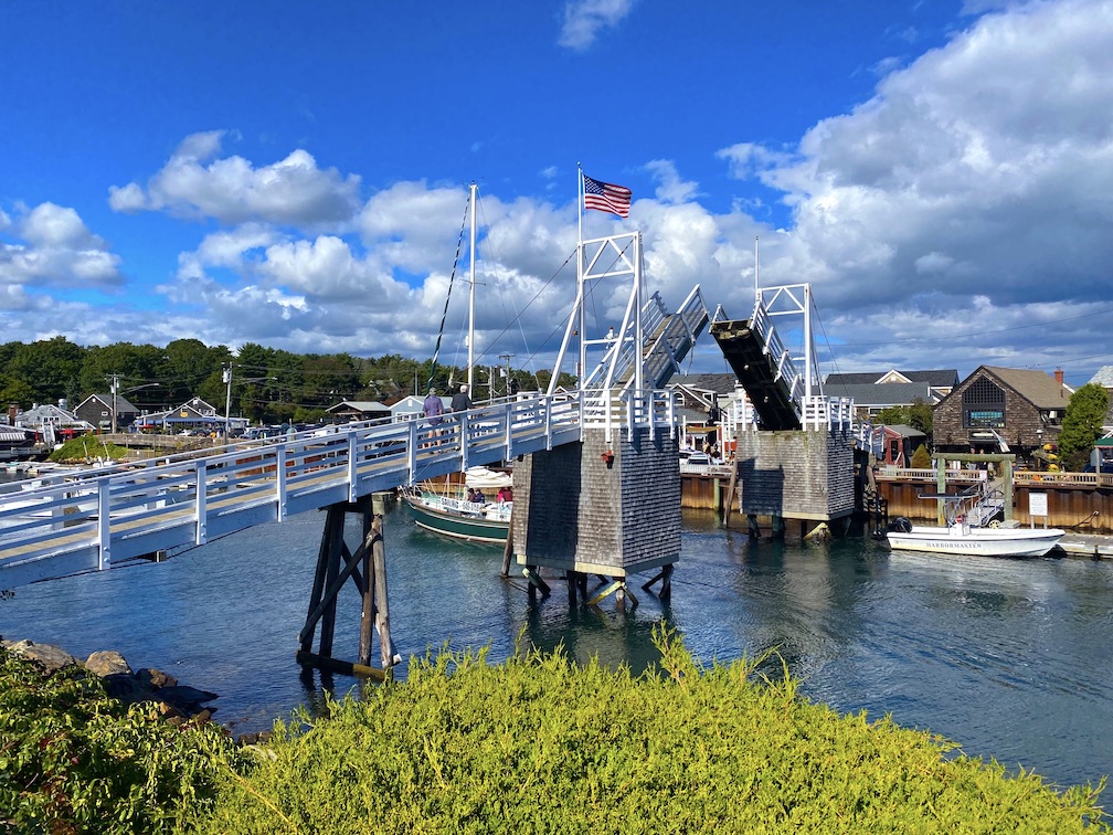 A sailboat entering harbor under the drawbridge in Perkins Cove in Ogunquit, Maine